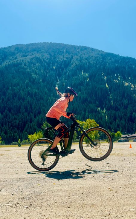E-MTB Camp Ultental 2026 E-MTB-Fahrerin fährt auf einem markierten Übungsplatz vor bewaldetem Berghang beim Fahrtechniktraining im Ultental.