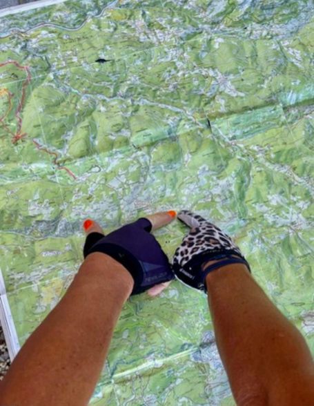 E-MTB Camp Dolomiti 2026 Behandschuhte Hände zeigen auf eine Karte bei der Tourenplanung für das E-MTB-Camp in den Dolomiten.