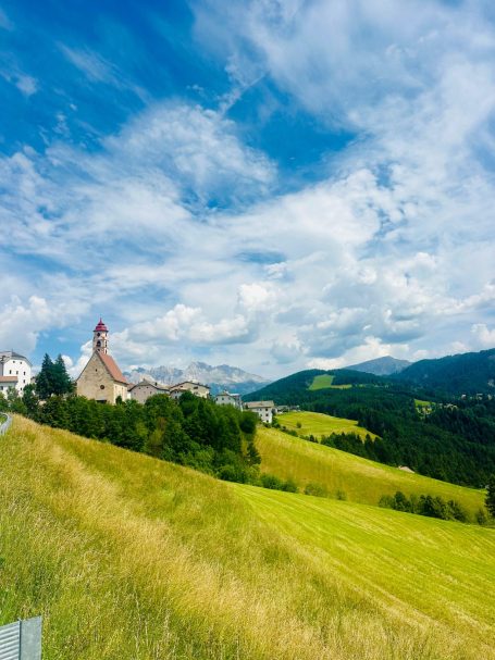 E-MTB Camp Dolomiti 2026 Kirche im Eggental auf einer grünen Hügellandschaft vor den Bergen entlang der Route des E-MTB-Camps Dolomiti.