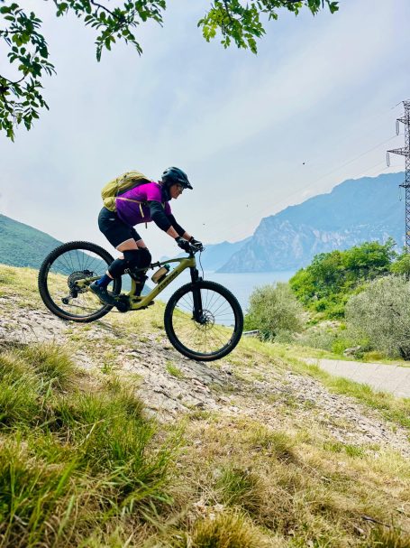E-MTB Camp Gardasee 2026 E-MTB-Fahrerin fährt auf einem felsigen Bergtrail oberhalb des Gardasees beim E-MTB-Camp für Frauen.
